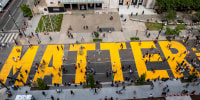 People walk down a street with the word "Matter" painted on it in bright yellow