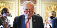 Chuck Schumer walks through a crowd of reporters