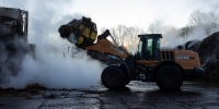 A person operates a wheel loader outside on a farm