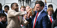 Image: Running back TreVeyon Henderson and Vice President JD Vance bobble the College Football Playoff National Championship Trophy