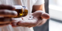 Young man spilling multiple pills in his hand.