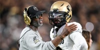 Deion Sanders, left, speaks to Shedeur Sanders on the football field