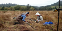 Pictured, from left to right, are Brandon Hatcher and Tina Dura walk across a field holding tools
