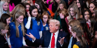 President Donald Trump is surrounded by girl athletes as he signs an executive order banning transgender athletes from participating in women's sports.