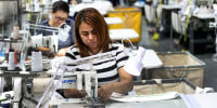 Workers sew on sewing machines in a factory