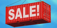 Large red shipping crate being lowered by a crane. The word "Sale!" is painted across the side of the crate in white letters.