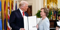 Donald Trump, left, holds a signed executive order folder open, and Linda McMahon stands to his right, looking at each other