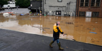 A man walks near a flooded area near the Swannanoa river
