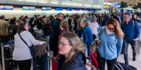 People wait in line for a delayed flight