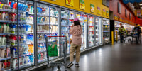 A customer browses refrigerated drinks in a grocery store.