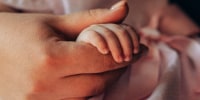 A close-up of a mother gently holding her baby's tiny hand,.