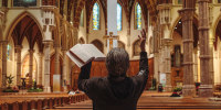 A person prays with their hands in the air