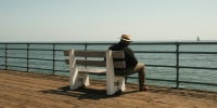 A man sat alone on a bench looking out at the sea