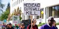 A person outside in a crowd holds a sign that says "Medicaid cuts will kill"
