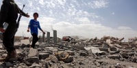 A security guard asks a child to stop walking over the rubble of a building destroyed by U.S. strikes on April 27, 2025 in Sana'a, Yemen. 