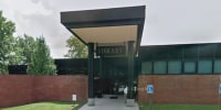 A library building is seen from the exterior from the parking lot