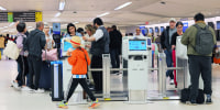 Passengers wait in line to check in for their flights 