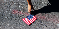 A boy reaches over to pick up a U.S. flag