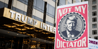  A marcher holds a sign that says, "Not My Dictator" with a picture of Donald Trump in front of Trump International Tower