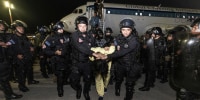 An alleged gang member escorted from a plane by El Salvador police