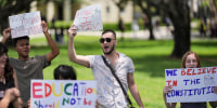 Students protest outside holding signs