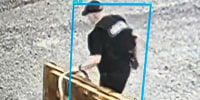 A footage screenshot of a person walking outside while wheeling items