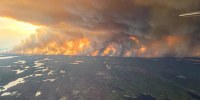 An aerial view of smoke billowing on the horizon