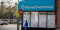 A person passes in front of a closed planned parenthood.