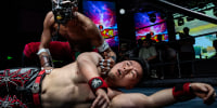 Wrestler Zombie Dragon, top, reacts as he tries to pin Coldplay during their match at the Middle Kingdom Wrestling Battle of the Decade in Beijing on May 24, 2025. 