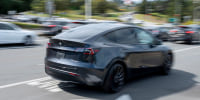 A Tesla Model Y vehicle drives near the company's store in Colma, Calif.