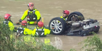 Emergency repsonders gather around a vehicle in flood waters in San Antonio, on June 12, 2025.
