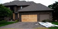 Boards cover the doors and windows outside of a home