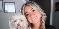 Caroline Dias Goncalves holds a dog and smiles for a portrait