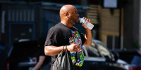 A man drinks water as he crosses a street during a heat wave in New York City on June 22, 2025.