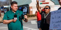 Mario Guevara holds a microphone and records with two phones outside next to protestors