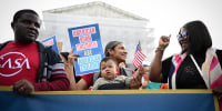 Olga Urbina holds her son, Ares Webster, nine months, as people gather outside the Supreme Court on May 15, 2025.