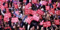 Democrats hold "We Fight, We Win" signs during the DNC