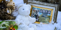 Flowers, a stuffed animal, and a framed image featuring the photos of the four people found dead at a house in Moscow, Idaho, rest in the snow in front of the house on Nov. 29, 2022. 