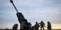 Ukrainian soldiers prepare a U.S.-supplied M777 howitzer to fire 