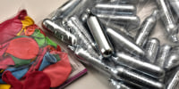 Balloons and nitrous oxide bottles are seen displayed on a table.