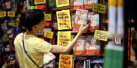 A member of staff places the comic book titled 'The Future I saw', authored by manga artist Ryo Tatsuki, on the shelf at Village Vanguard book store in Tokyo