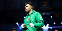 Julio César Chávez Jr. stands in the boxing ring wearing a green sweater and sweatpants