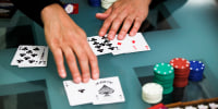 Niman Kenkre plays poker, his hands are seen on a table with playing cards and poker chips