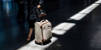 A traveler pushes a suitcase inside of an airport
