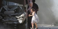 A Palestinian mother and her daughter rush for cover during an Israeli strike