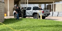 Officials work the scene of a shooting outside, a truck is parked outside with agents surrounding it