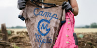 A search and rescue volunteer holds a T-shirt and backpack with the words Camp Mystic on them