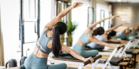 Group of people doing the pilates exercise or side stretch to tone the intercostal muscles viewed from the rear.