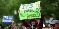 A person holds a green sign that reads "TPS 4 Central America"