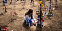 A woman sits on the ground as she attends the celebrations of the Israel's annual Memorial Day for the fallen soldiers at the site where revelers were killed and kidnapped on Oct.
